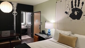 Une chambre d’hôtel équipée d’un lit, d’un bureau, d’une lampe et d’un mur décoré d’un motif représentant une empreinte de main.