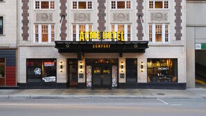 Un bâtiment avec une enseigne lumineuse indiquant « ACME HOTEL COMPANY » et une autre indiquant « CHAMBRES LIBRES ».