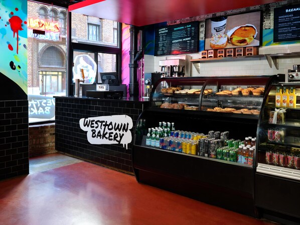 Un comptoir de boulangerie avec un menu, une caisse enregistreuse et une vitrine où sont exposés les produits de boulangerie.