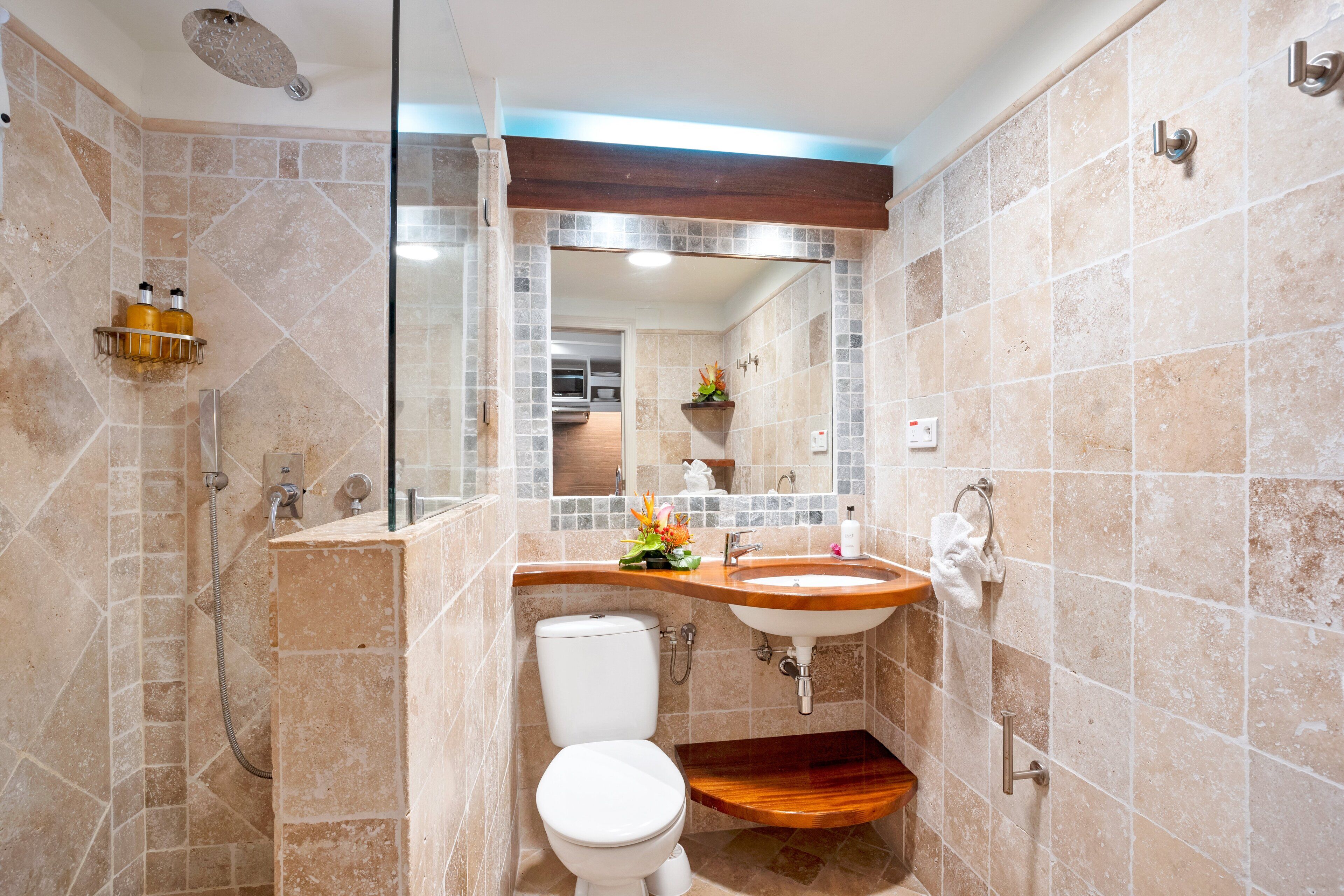Un baño con ducha, inodoro, lavabo y tocador de madera.