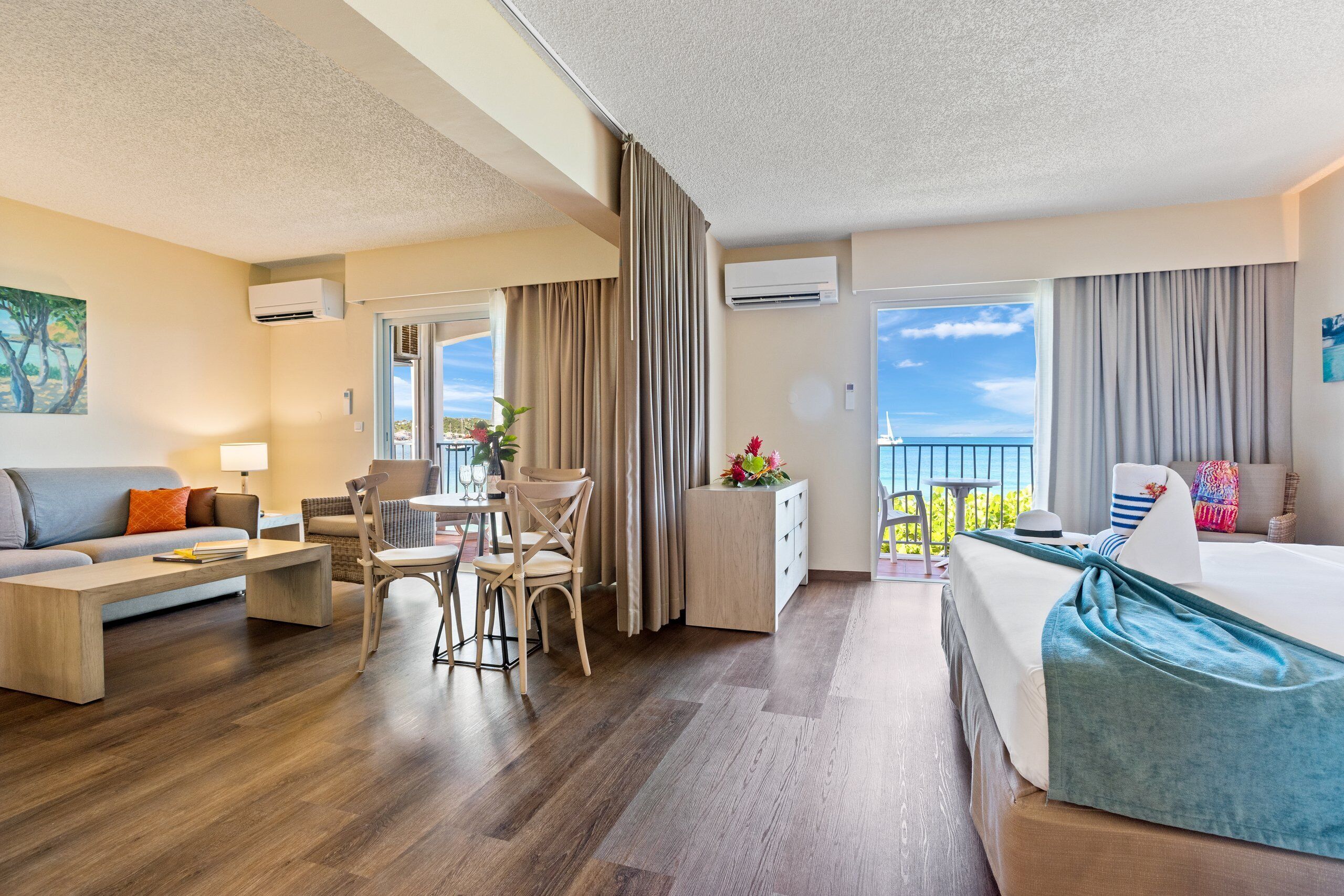 A hotel room with a balcony, a dining area, and a bed.