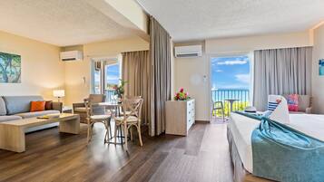 A hotel room with a balcony, a dining area, and a bed.