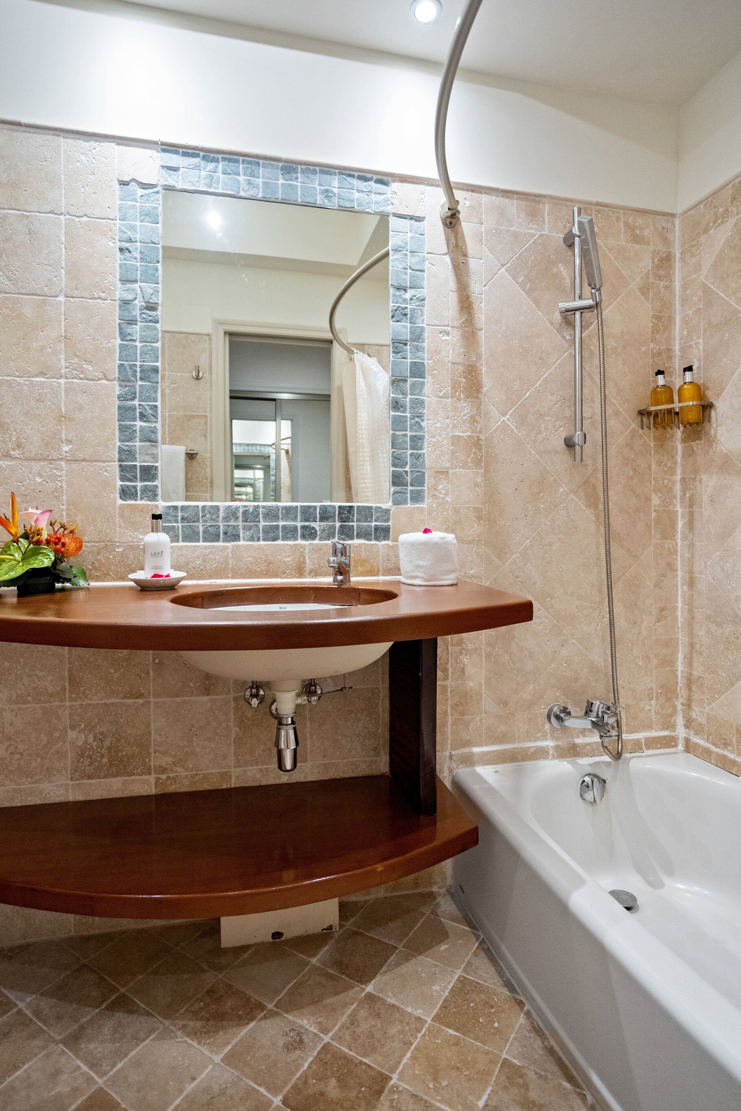 A bathroom with a sink, mirror, and bathtub.