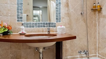 A bathroom with a sink, mirror, and bathtub.