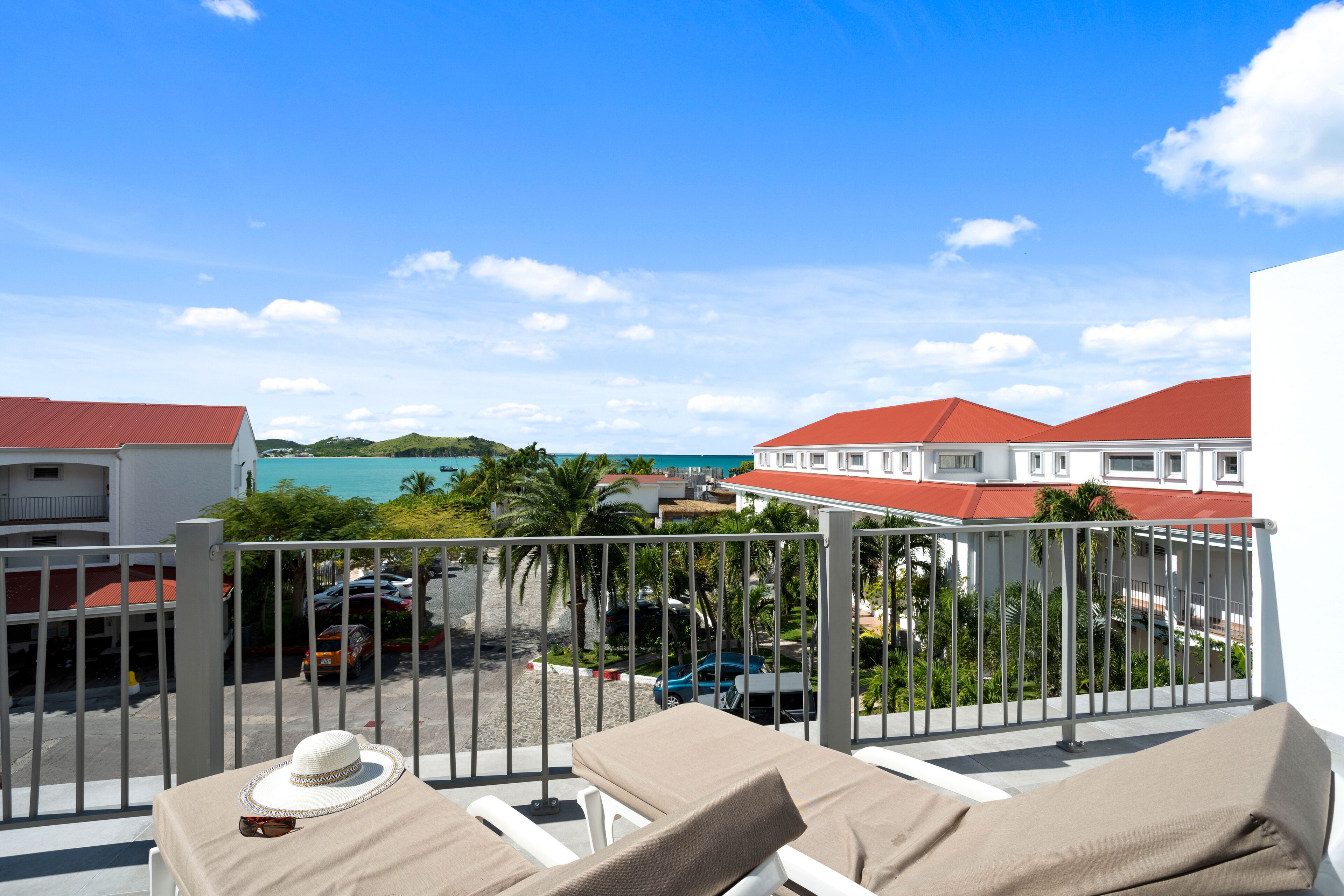 A balcony with two lounge chairs, a table, and a hat.