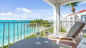 Un balcon avec vue sur l’océan, deux verres à vin et une chaise.