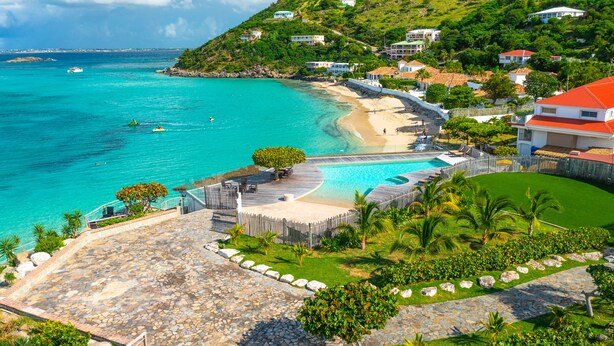 Une station balnéaire dotée d’une piscine, d’un accès à la plage et d’une végétation luxuriante.