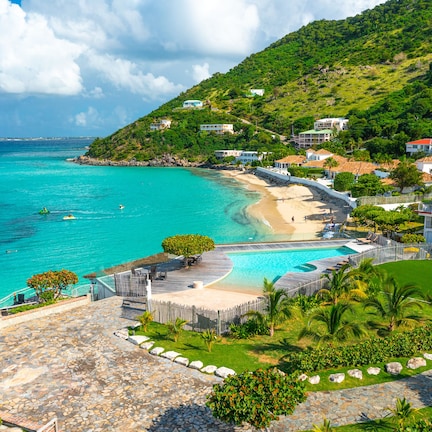 A coastal resort with a swimming pool, beach access, and lush greenery.