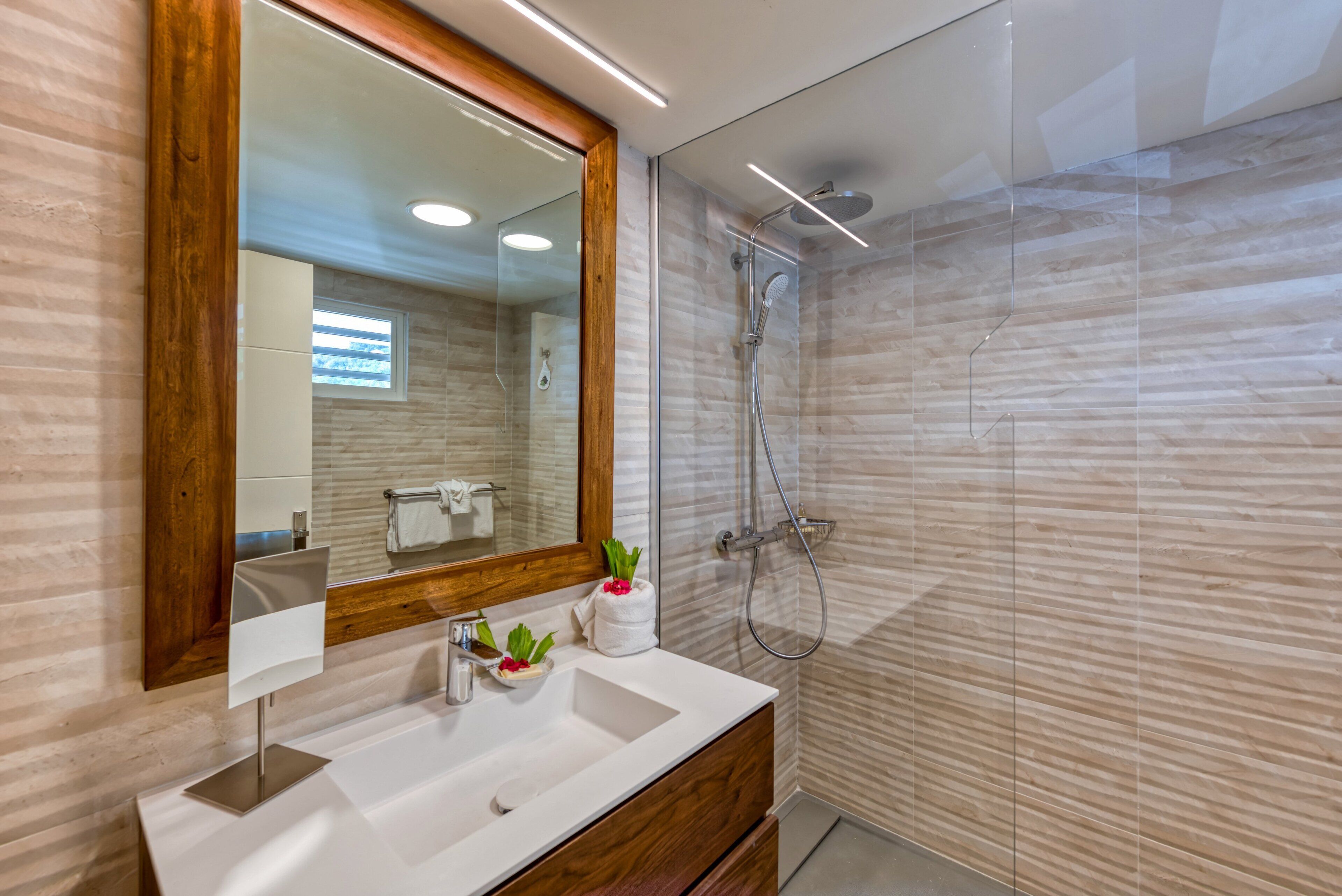 Un baño moderno con un espejo grande, un lavamanos y una ducha.