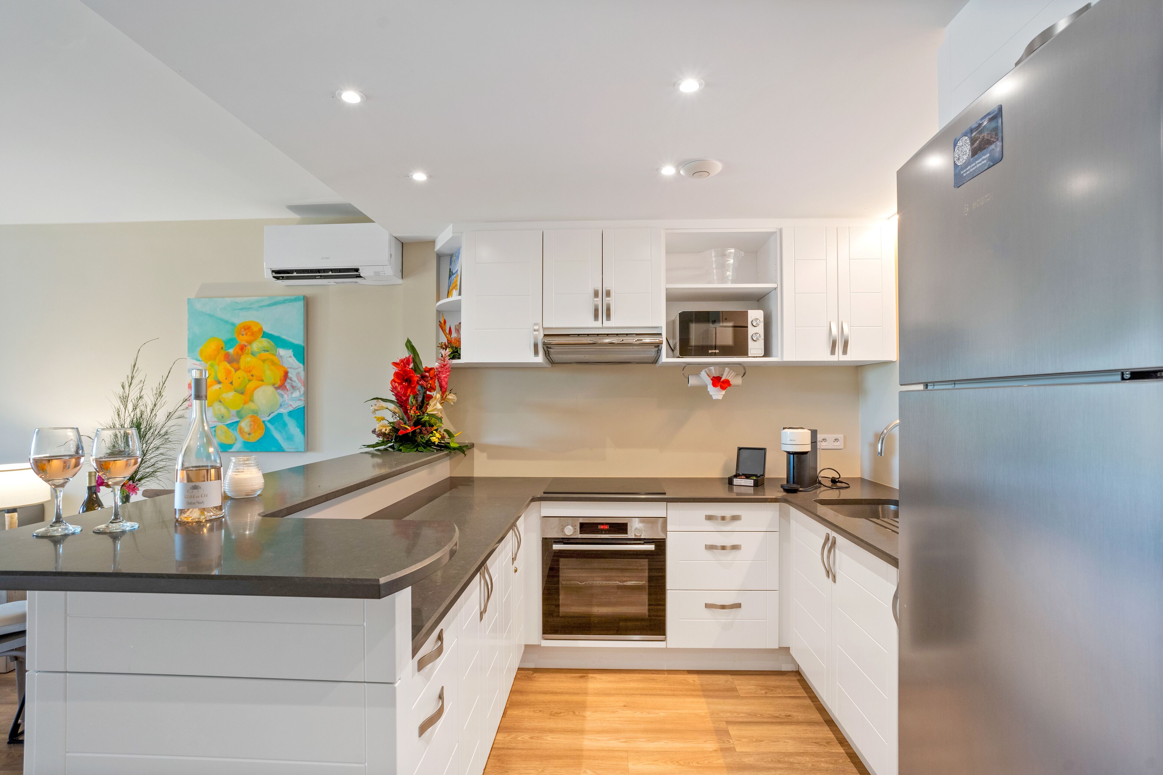 Una cocina moderna con armarios blancos, un refrigerador de acero inoxidable, un microondas y un horno.