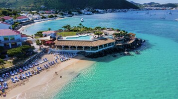 Vista aérea de un complejo turístico en la costa con piscina, playa y vistas al océano.