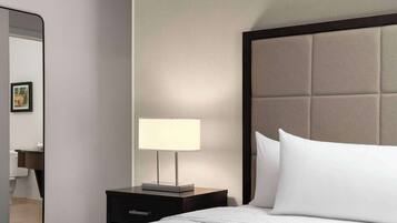 A hotel room with a bed, a bedside table with a lamp, a mirror, and a headboard.