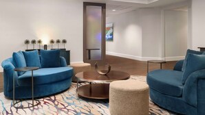 Un salon moderne avec un canapé bleu, une table basse ronde et une petite table d’appoint.