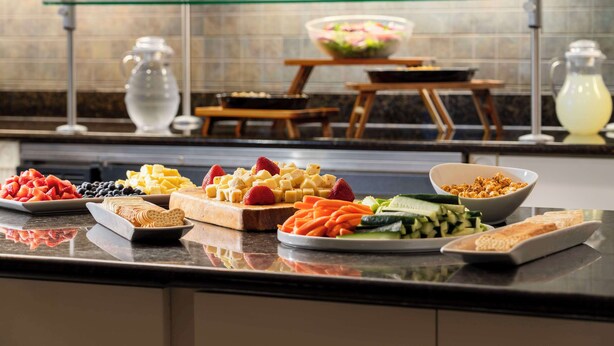 Un buffet proposant une variété d’aliments, notamment des fruits, des fromages et des légumes.