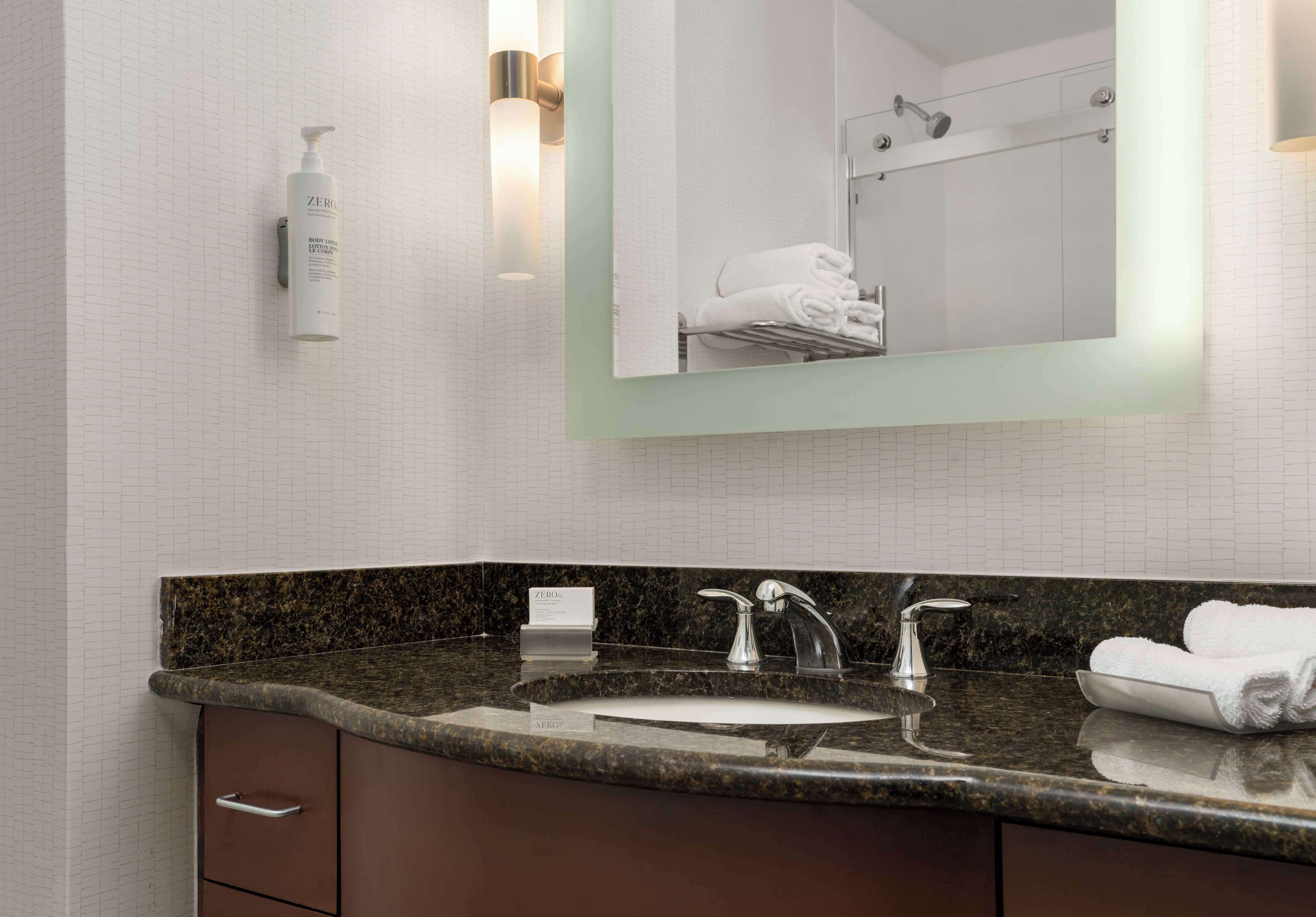 Baño con lavamanos de encimera de granito, espejo y toallero.