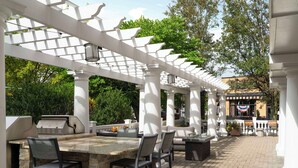 Une terrasse extérieure dotée d’un barbecue, d’un espace salon et d’une pergola.