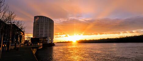 A high-rise hotel with a waterfront view during sunset.