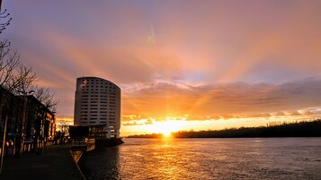 A high-rise hotel with a waterfront view during sunset.
