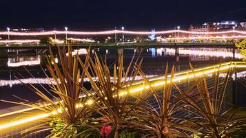 A nighttime view of a waterfront area with illuminated pathways and a body of water reflecting lights.