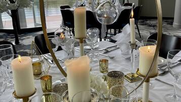Mesa dispuesta para un evento formal con velas blancas, detalles dorados y cristalería transparente.