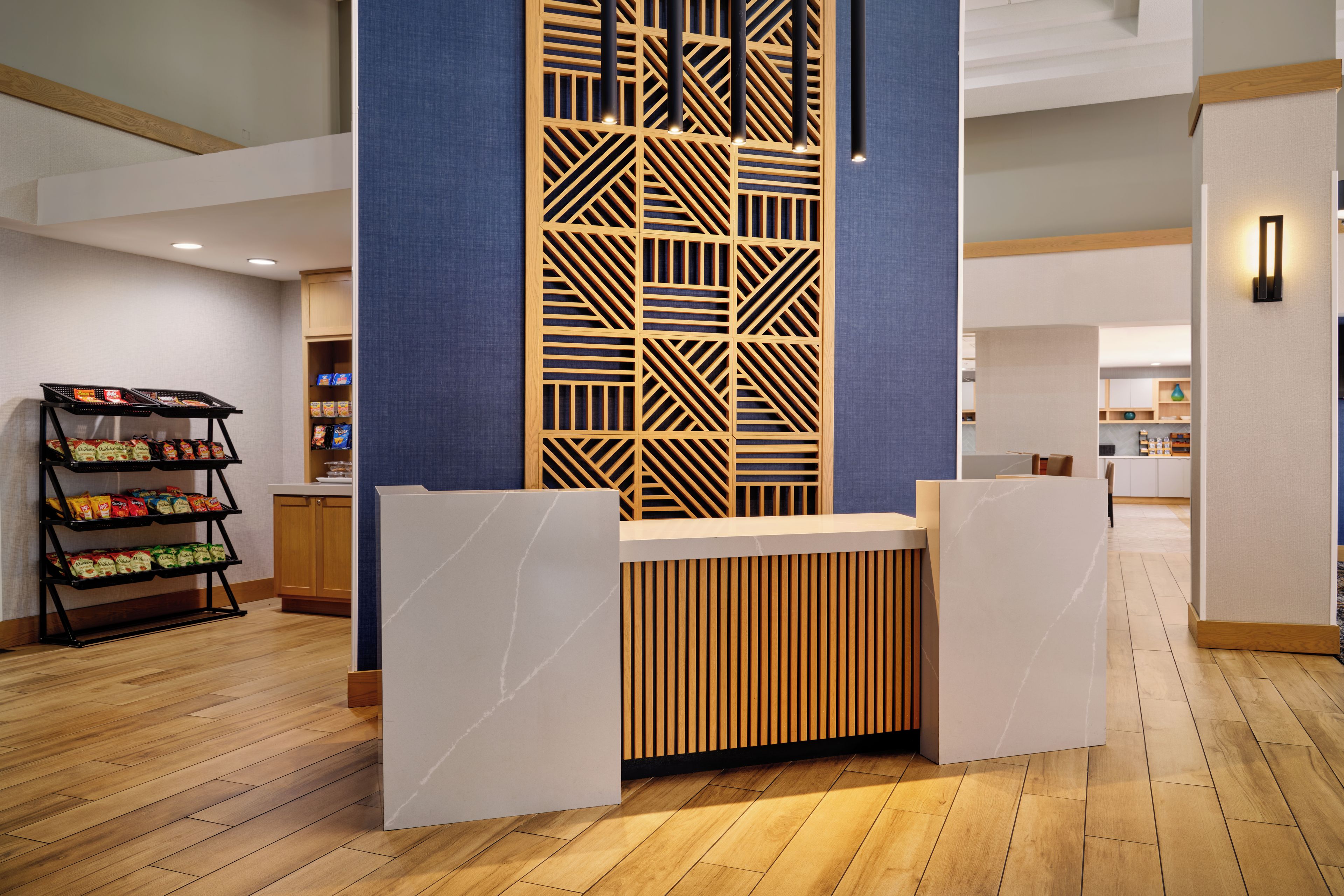 Un espace d’accueil avec un séparateur en bois, un bar proposant des collations emballées, et un aménagement intérieur moderne.