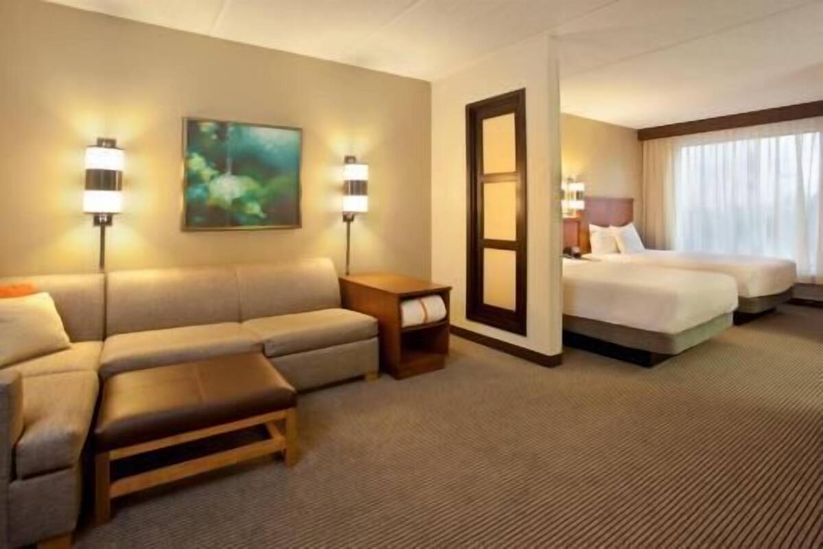 Ein Hotelzimmer mit einer Couch, einem Bett, einem Nachttisch und einem Bild an der Wand.