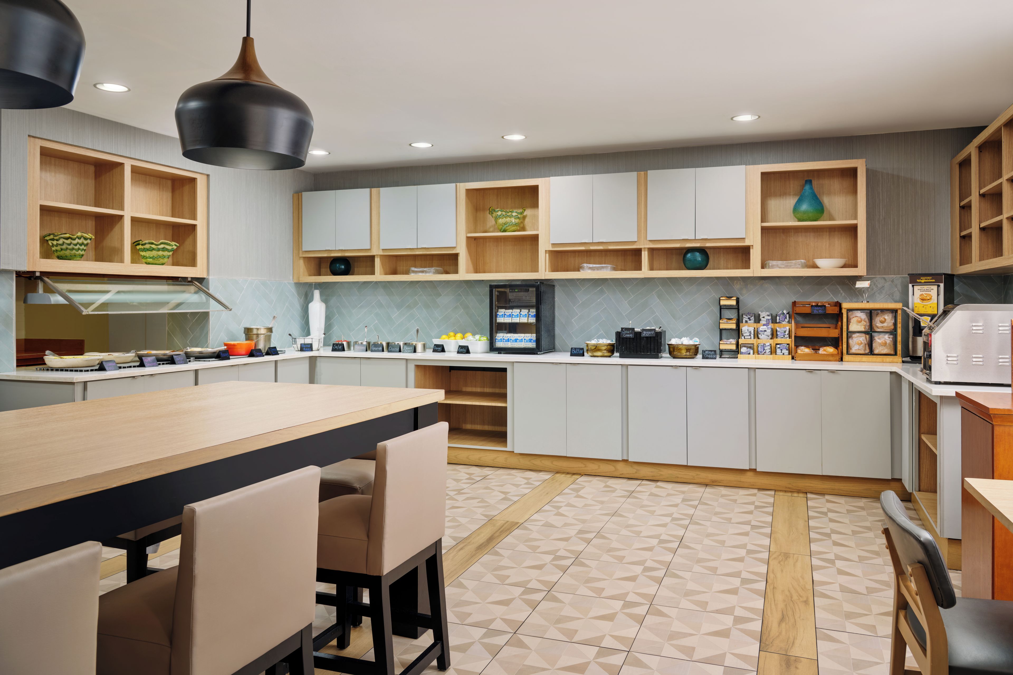 A modern kitchen with wooden cabinets, a central island, and a dining area with chairs.