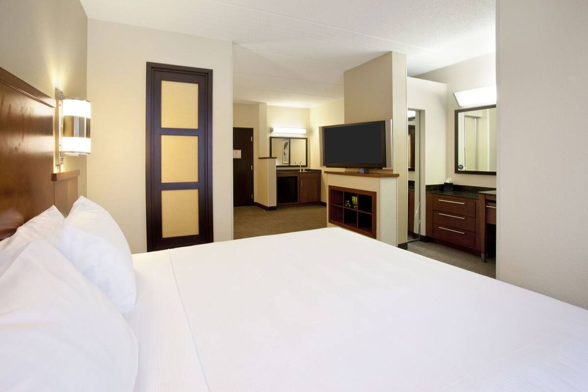 Ein Hotelzimmer mit Bett, Fernseher, Schreibtisch und Spiegel.