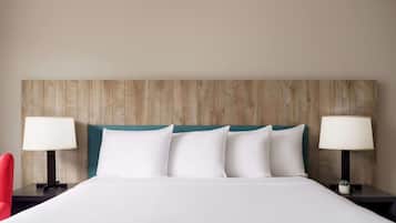 A hotel room with a wooden headboard, white bedding, and two bedside lamps.