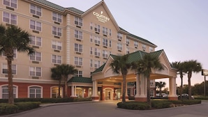 A large hotel with a prominent entrance, multiple floors, and a covered area with palm trees.