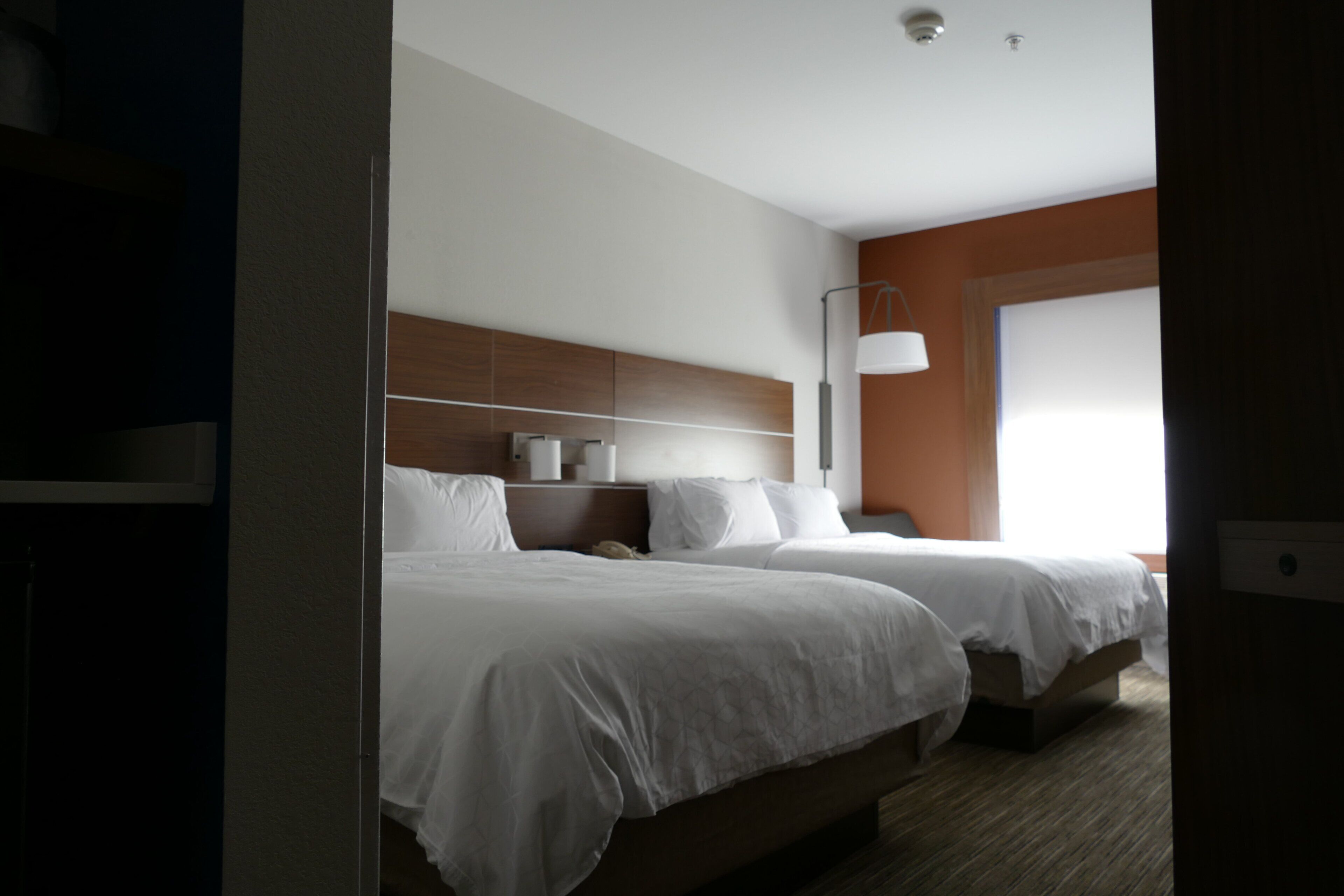 Et hotelværelse med to senge, et natbord, en lampe og et vindue.