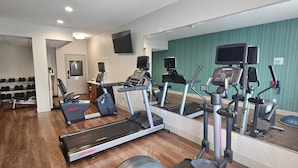 A home gym with treadmills, an elliptical, and a weight bench. - Holiday Inn Express Greensburg by IHG (Greensburg)