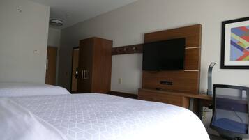 Habitación de hotel con dos camas, televisión, escritorio con silla y armario.