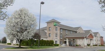 Edifício Holiday Inn Express com fachada de tijolos, entrada coberta e estacionamento.