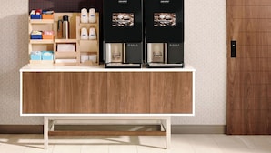 A modern kitchen with a wooden countertop, two coffee machines, and a built-in shelf with various items. - Holiday Inn Express Greensburg by IHG (Greensburg)