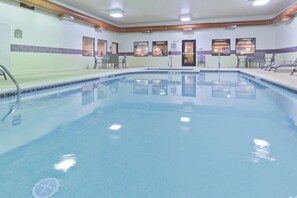 A large indoor swimming pool with clear water, surrounded by lounge chairs and a tiled wall with a 'No Diving' sign. - Holiday Inn Express Greensburg by IHG (Greensburg)