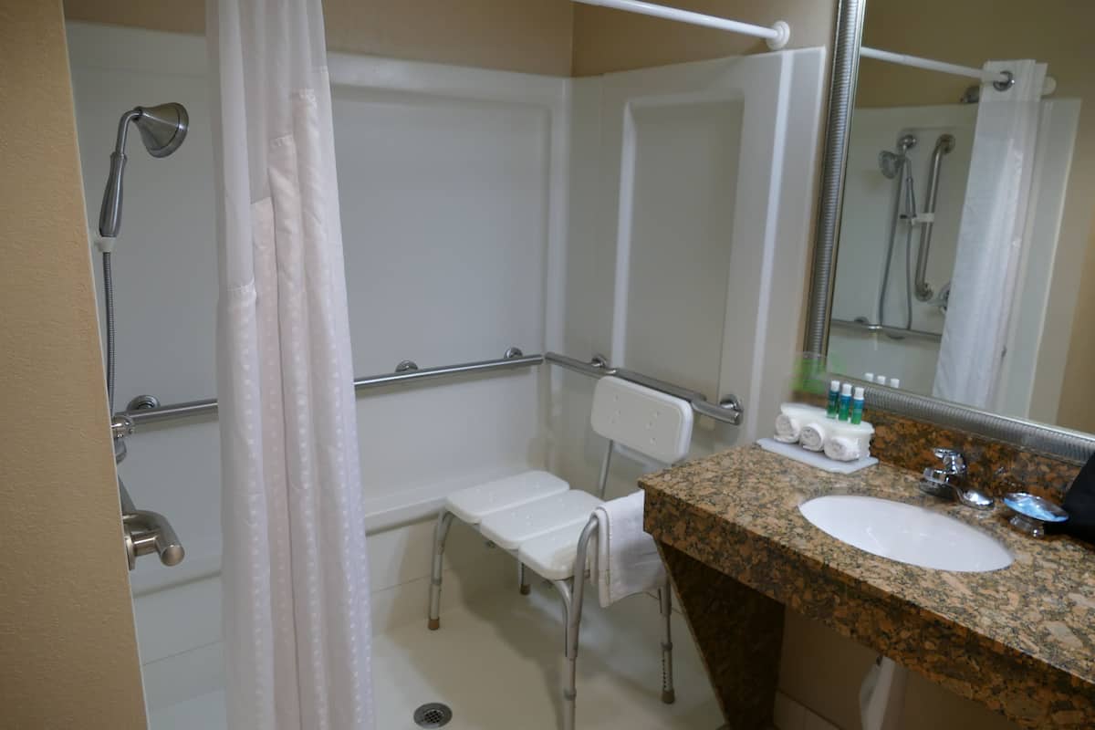 Un baño con ducha, un lavamanos blanco y un espejo.