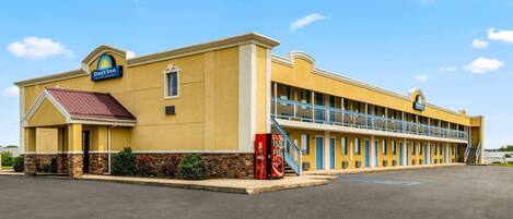 A Days Inn building with a yellow facade, a red awning, and a Coca-Cola vending machine.