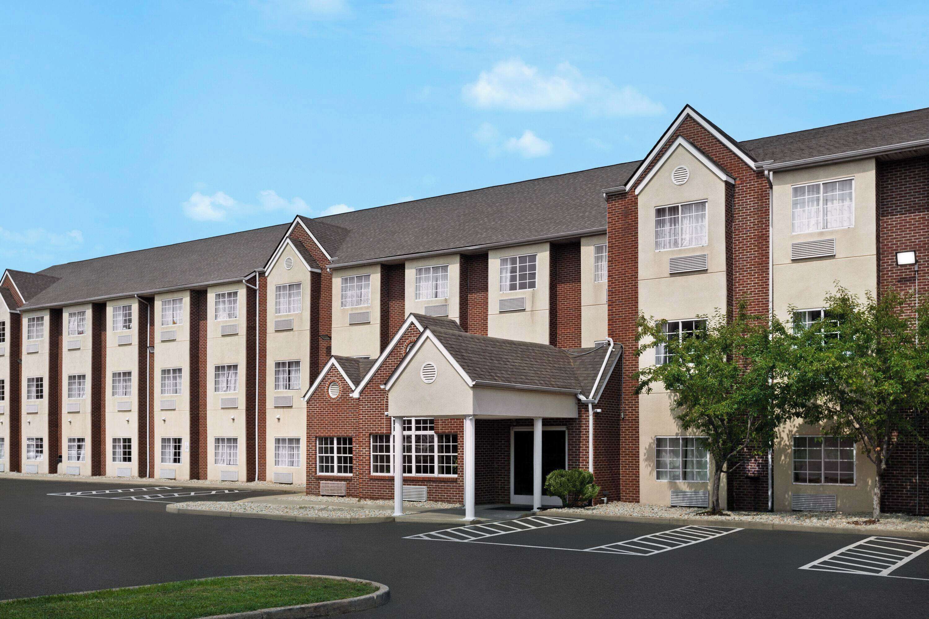 A multi-story hotel with a brick facade, a covered entrance, and a parking lot.