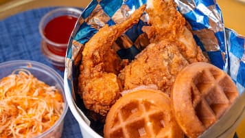 Un cestino con pollo fritto, waffle e una porzione di formaggio grattugiato.