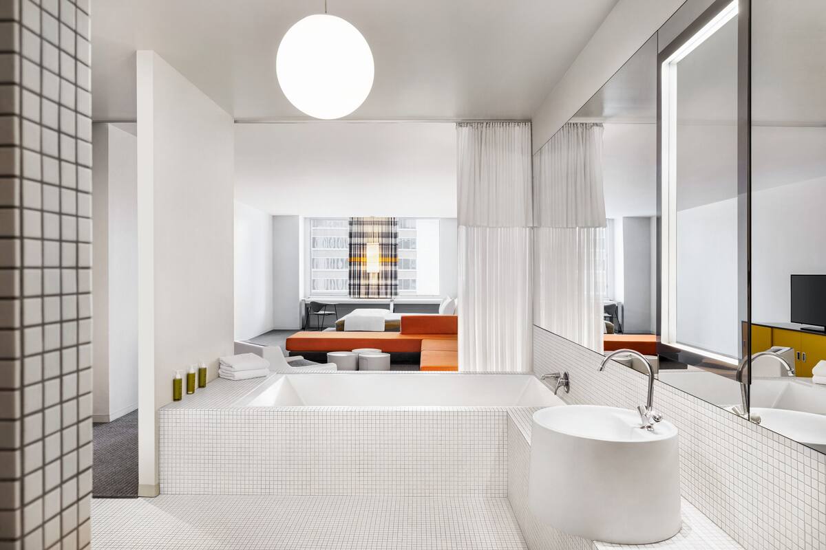A modern bathroom with a large bathtub, a round sink, and a mirror.