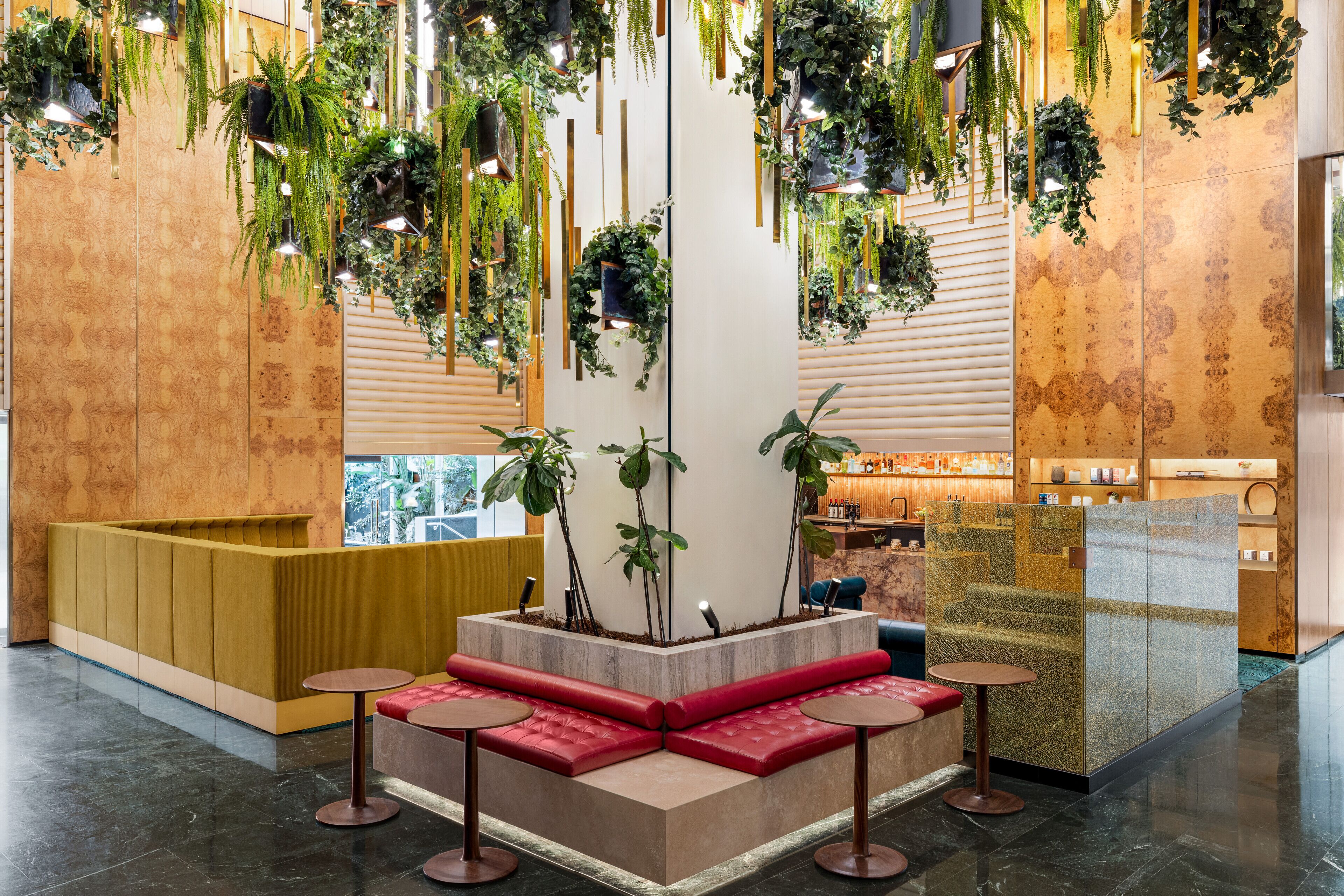 A modern lobby with a central seating area, a bar, and hanging plants.