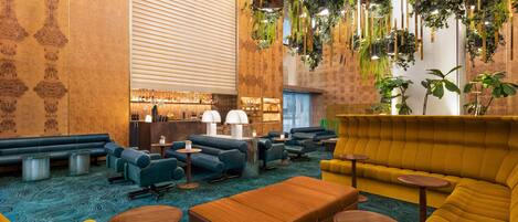 A modern lounge area with sofas, tables, and hanging plants.