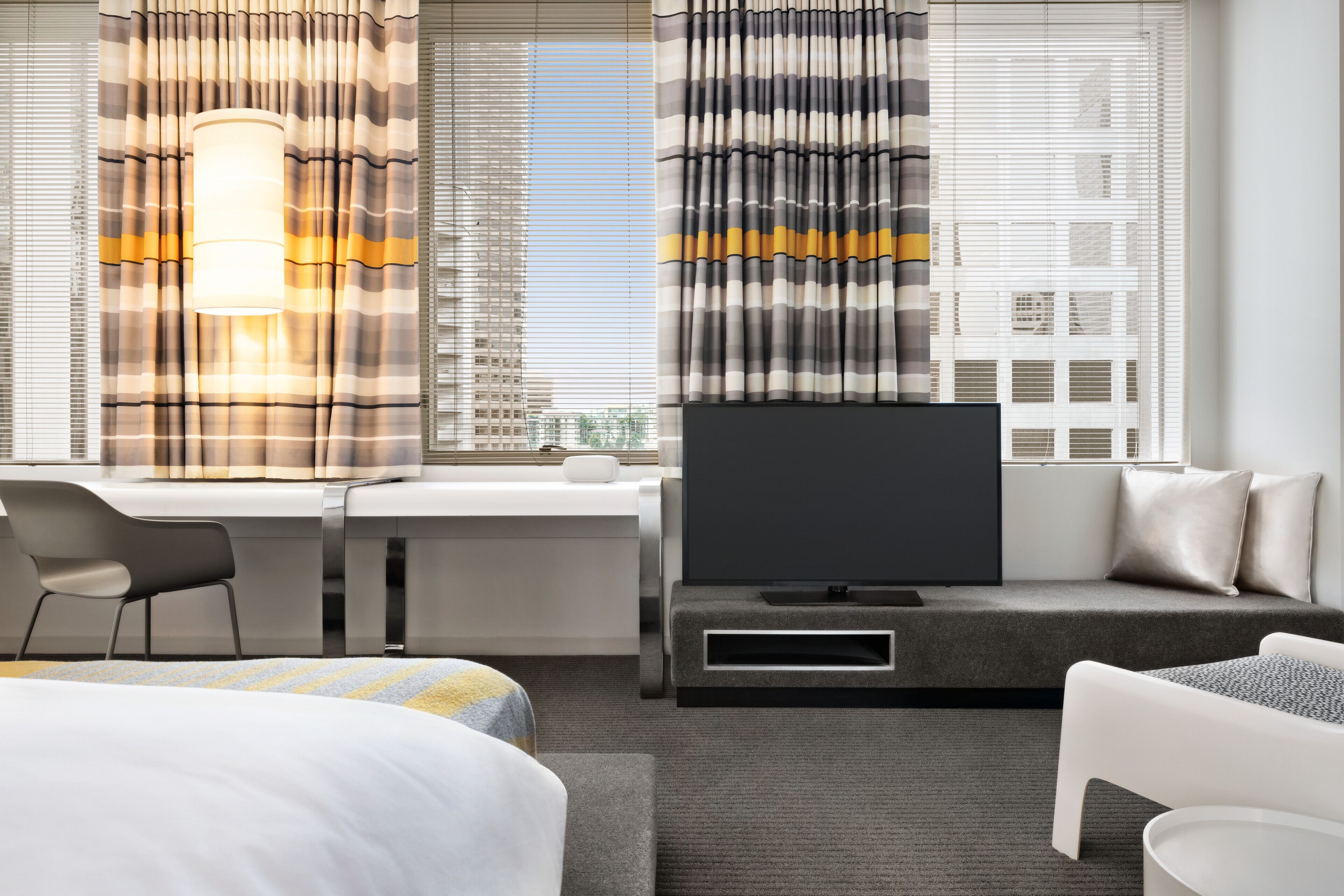 Una habitación de hotel moderna con cama, escritorio, televisor y sofá.