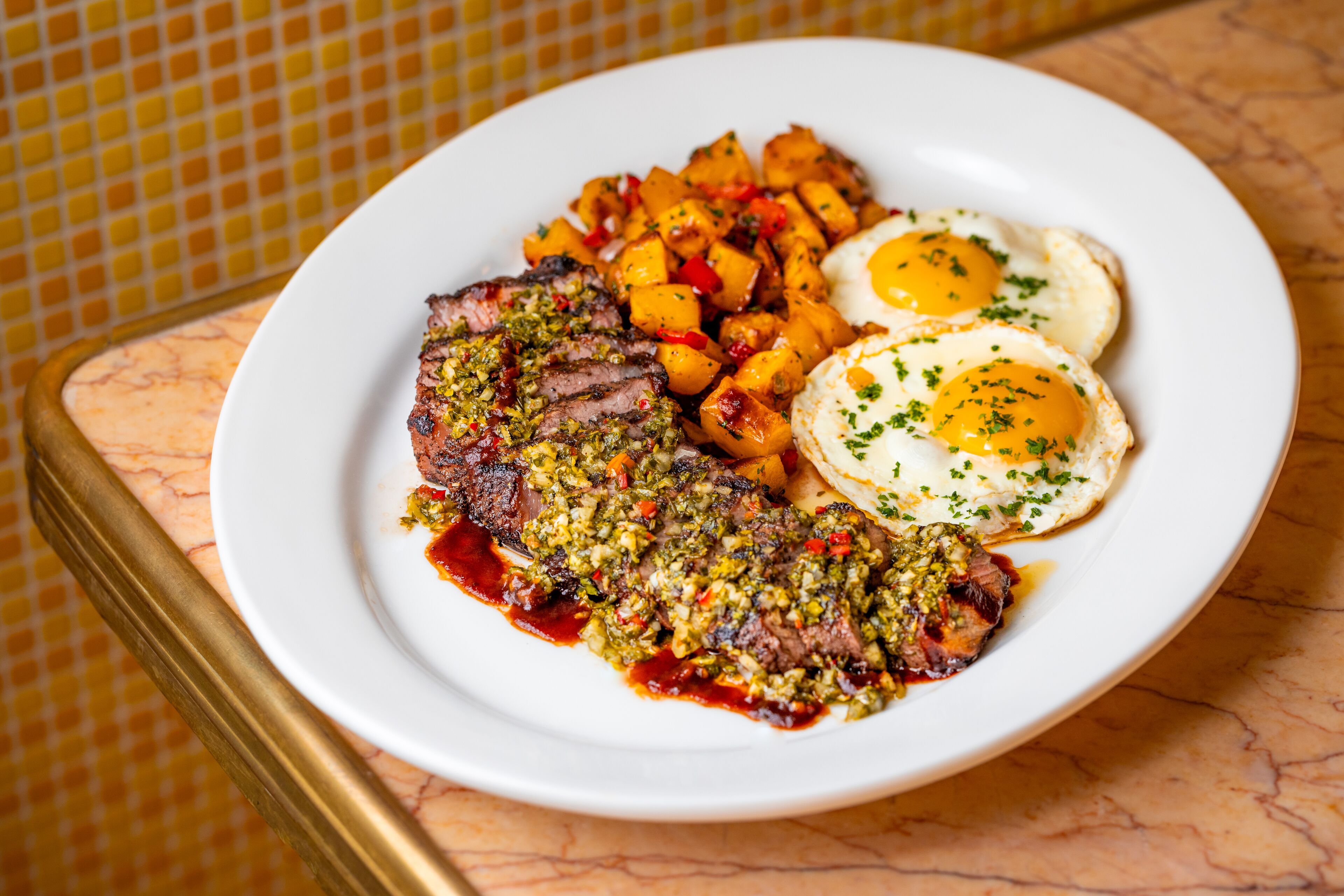 A plate of food with steak, eggs, and potatoes.