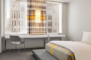 A hotel room with a bed, a desk, and a chair.