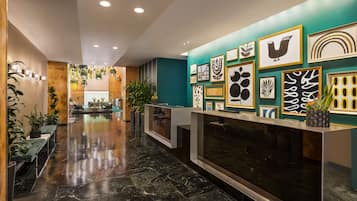 A modern lobby with a reception desk, seating area, and wall-mounted artwork.