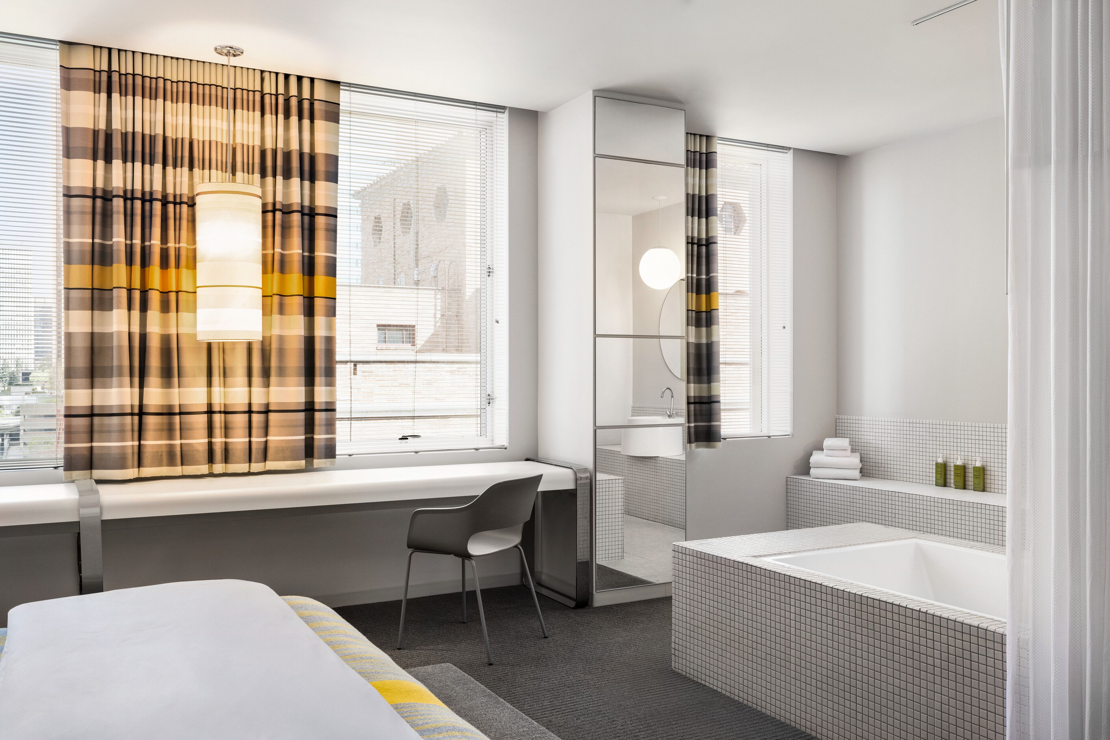 Un baño moderno con bañera, ducha y ventana con cortinas.