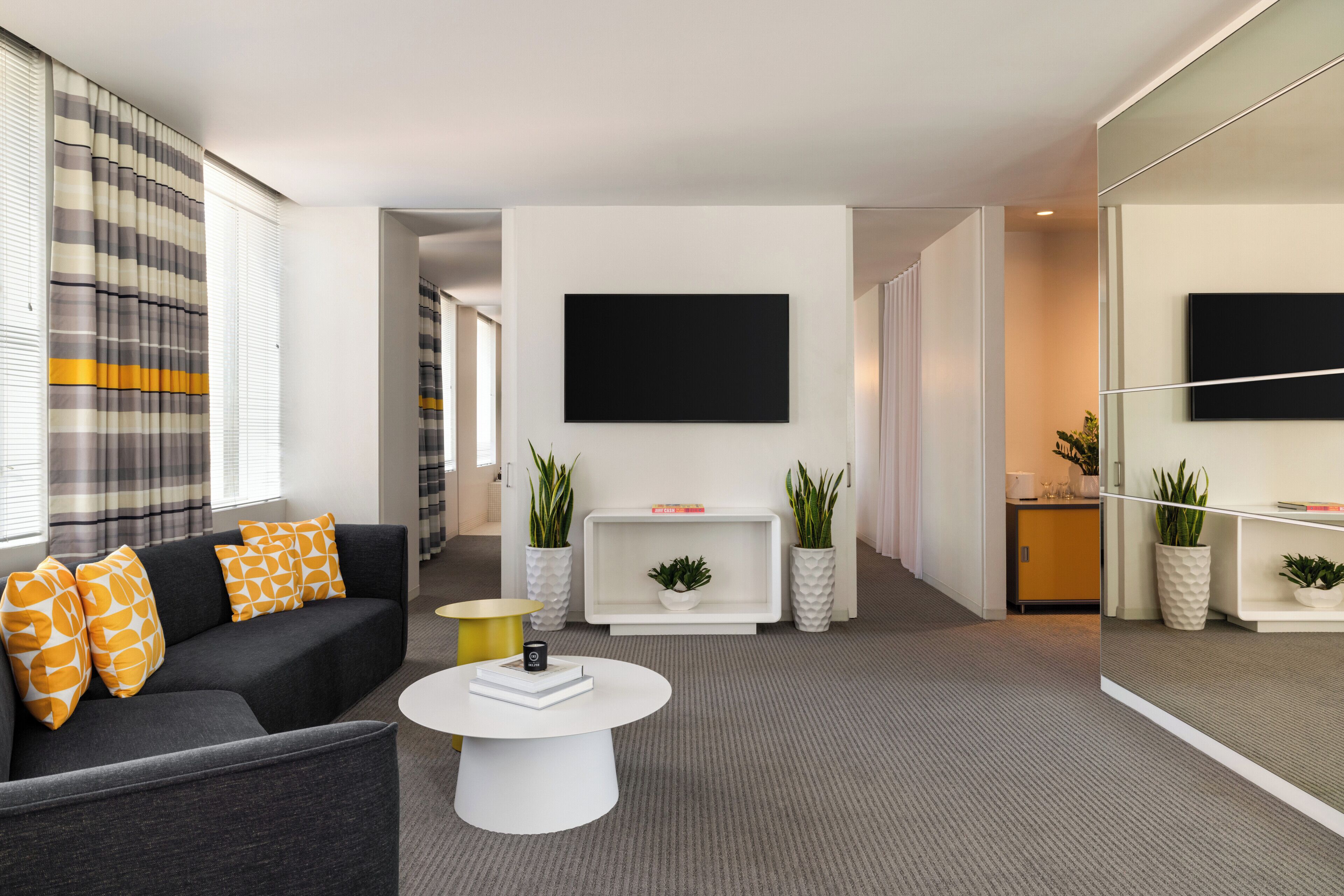A modern living room with a sofa, coffee table, and a flat-screen TV mounted on the wall.