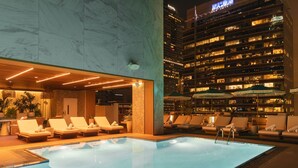 Una piscina interior con sillas de descanso y vistas a un rascacielos de noche.